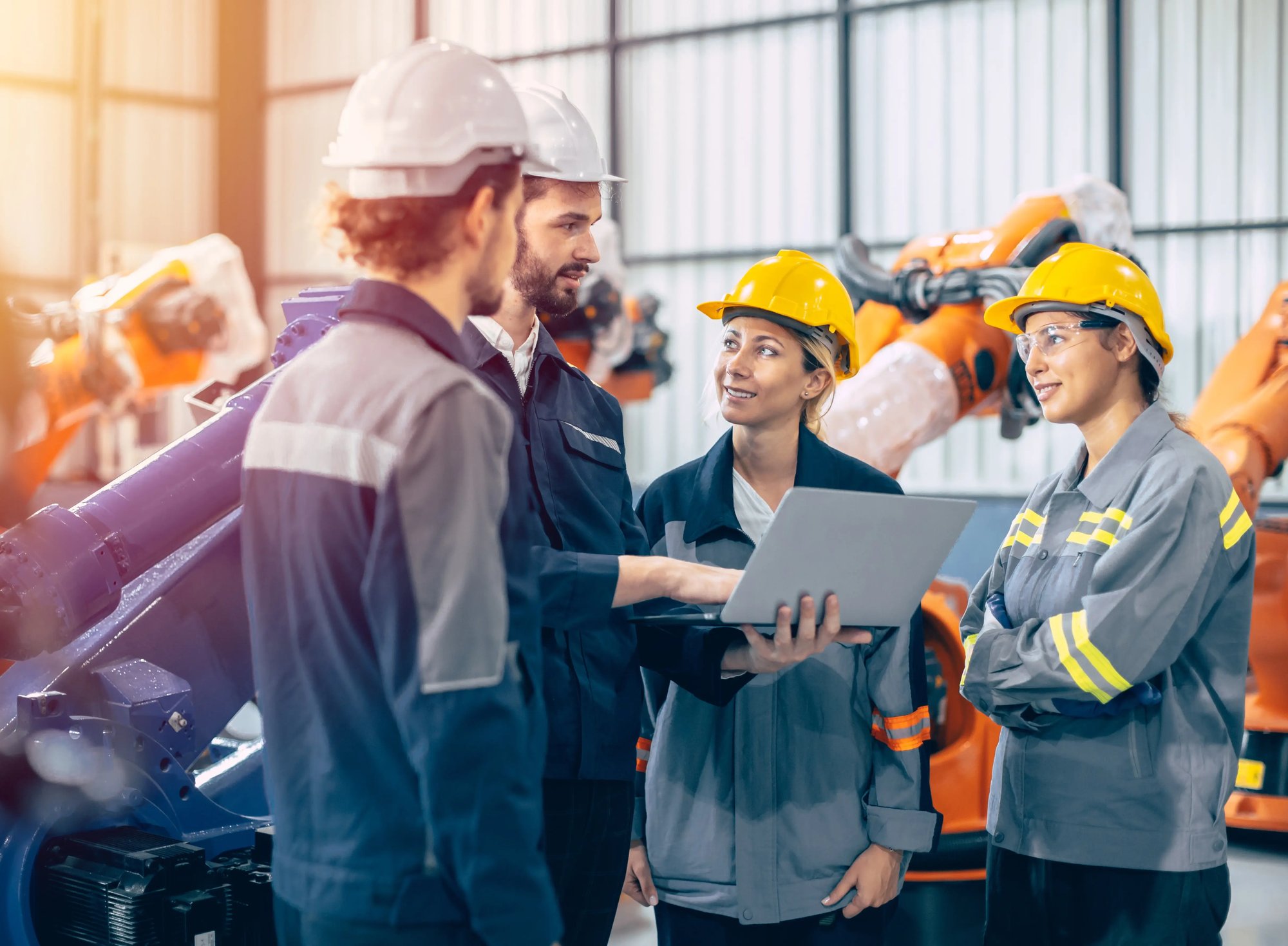 Groupe de collègues dans une usine avec des bras robots autour d'eux